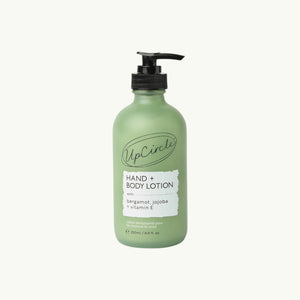 UpCircle hand and body lotion in a frosted green glass bottle with a black pump dispenser and bergamot scent label