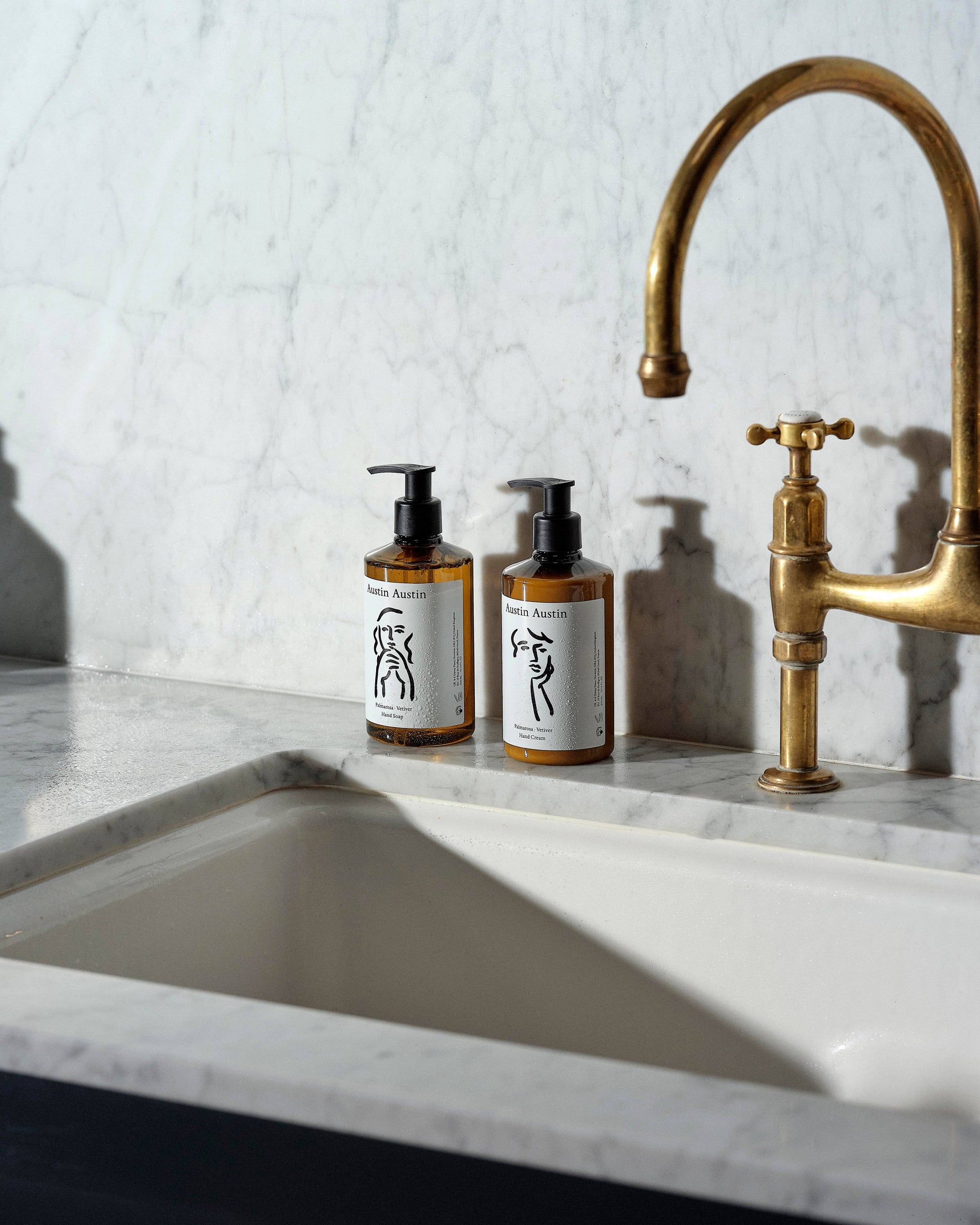 Austin Austin Palmarosa and Vetiver Hand Cream 300ml bottle alongside the matching Hand Soap 300ml, arranged on next to a kitchen sink