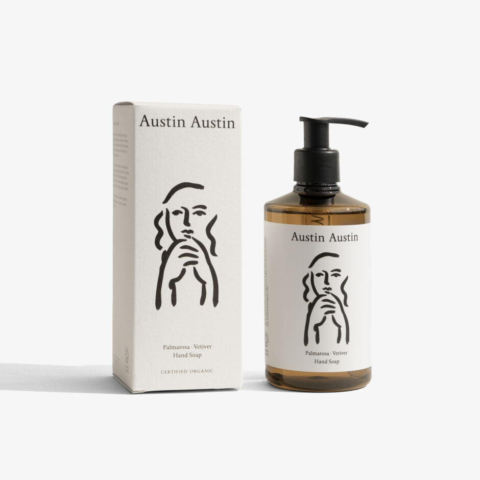 Austin Austin Palmarosa and Vetiver Hand Soap 300ml amber glass bottle with black pump dispenser standing next to its white outer box, both displaying the Christian Newby figurative line drawing, front-facing studio shot