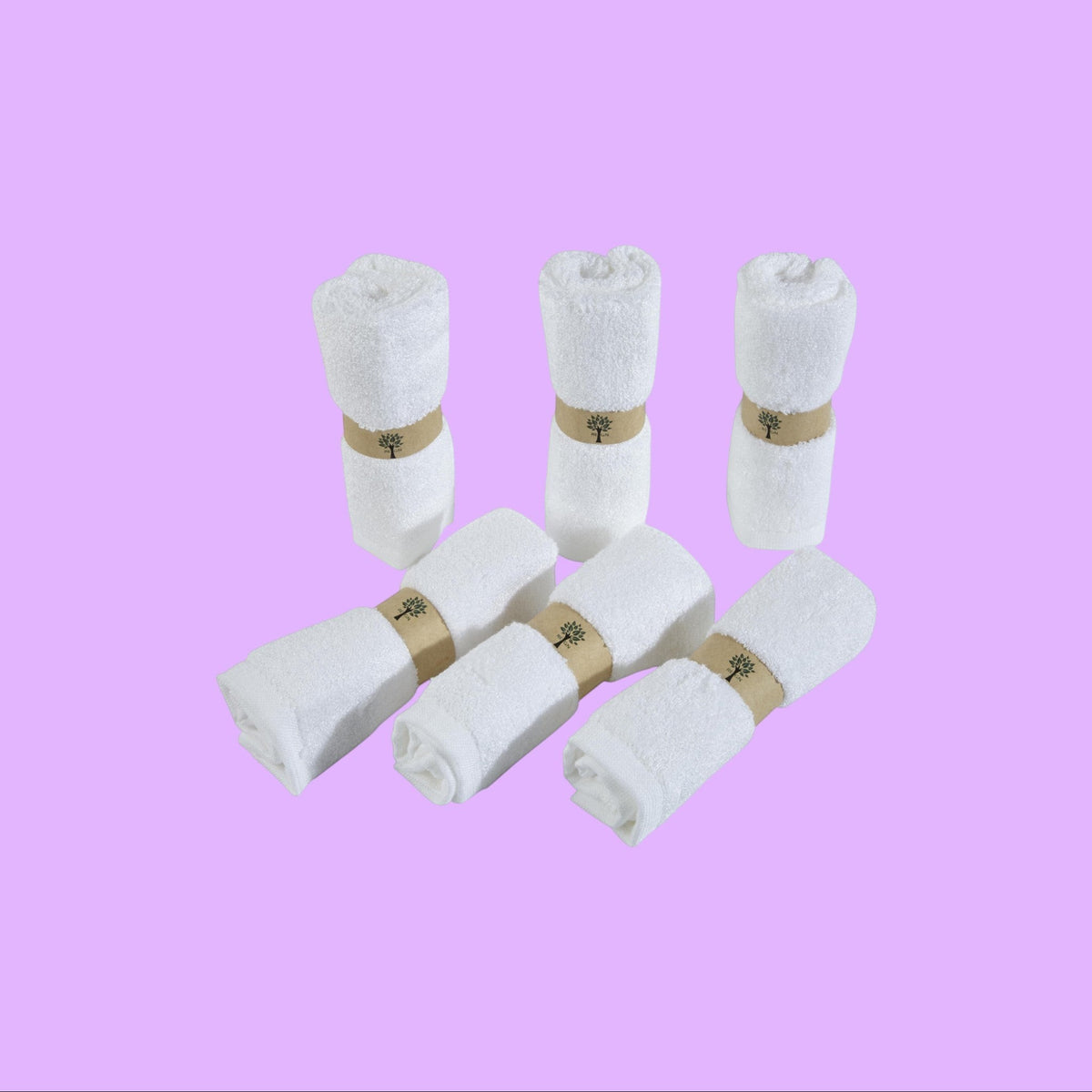 Re:gn set of six white organic bamboo face cloths rolled and secured with eco-friendly paper bands, shown from a different angle.