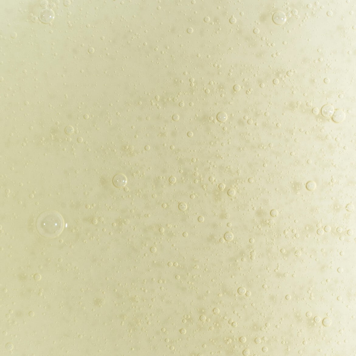 Close-up of the UpCircle Hand and Body Wash pale yellow-green gel formula showing the lightweight liquid consistency with fine bubbles