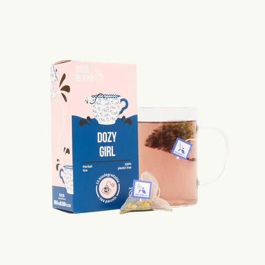 Bird and Blend Dozy Girl chamomile herbal tea box with a glass mug and a biodegradable tea bag on a light background