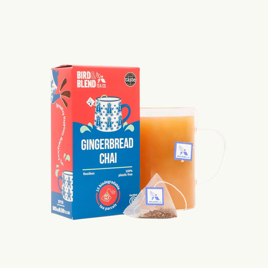 Bird and blend Gingerbread Chai tea box and plastic-free pyramid tea bag next to a glass mug of brewed rooibos chai tea.