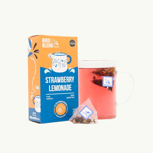 Bird and blend Strawberry Lemonade fruit tea box with a glass mug of pink tea and a biodegradable pyramid tea bag
