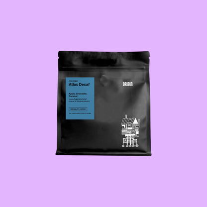 Origin Coffee Atlas Decaf whole bean coffee in a black pouch with a blue label featuring tasting notes of apple and chocolate.