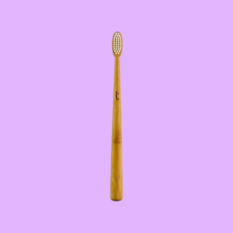 Truthbrush bamboo toothbrush with a slim head and soft white plant-based bristles against a light purple background