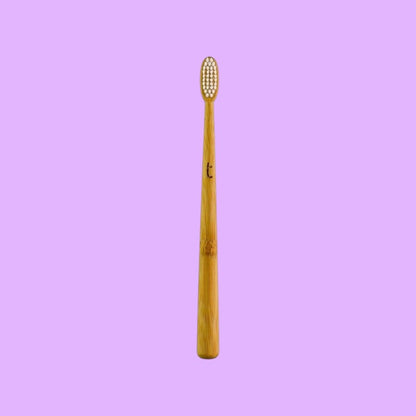 Truthbrush bamboo toothbrush with a slim head and soft white plant-based bristles against a light purple background