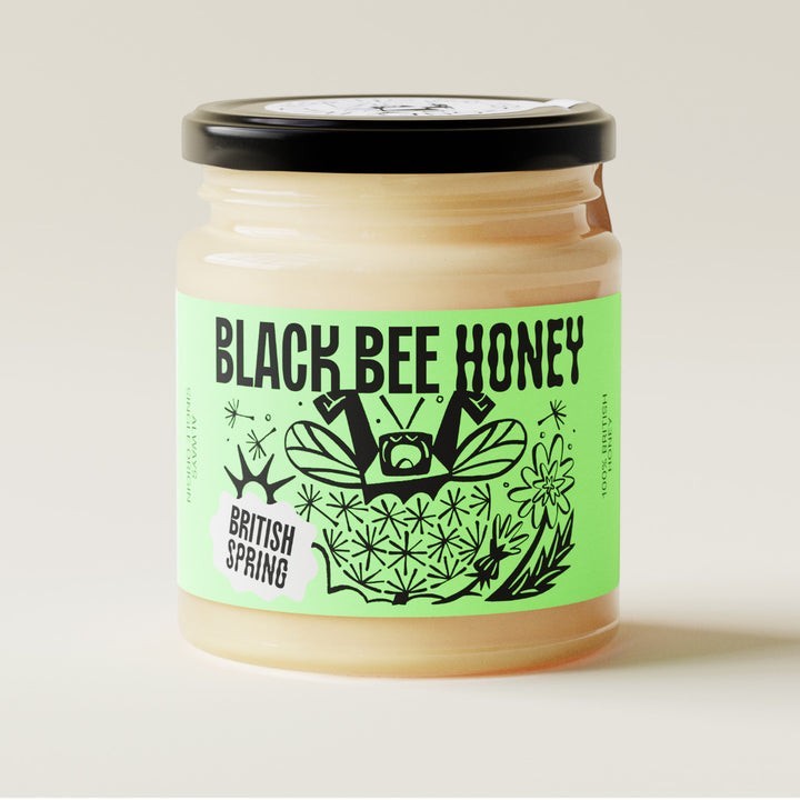 Black Bee Honey British Spring soft-set honey in a glass jar with a vibrant green illustrated label