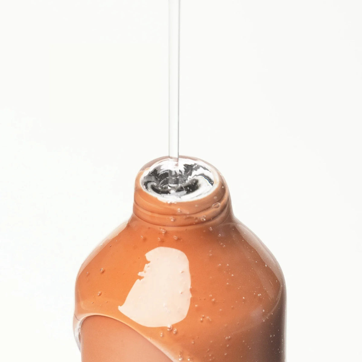 Kinfill Body Wash Starter Kit in a refillable aluminium bottle with clear liquid pouring into the opening
