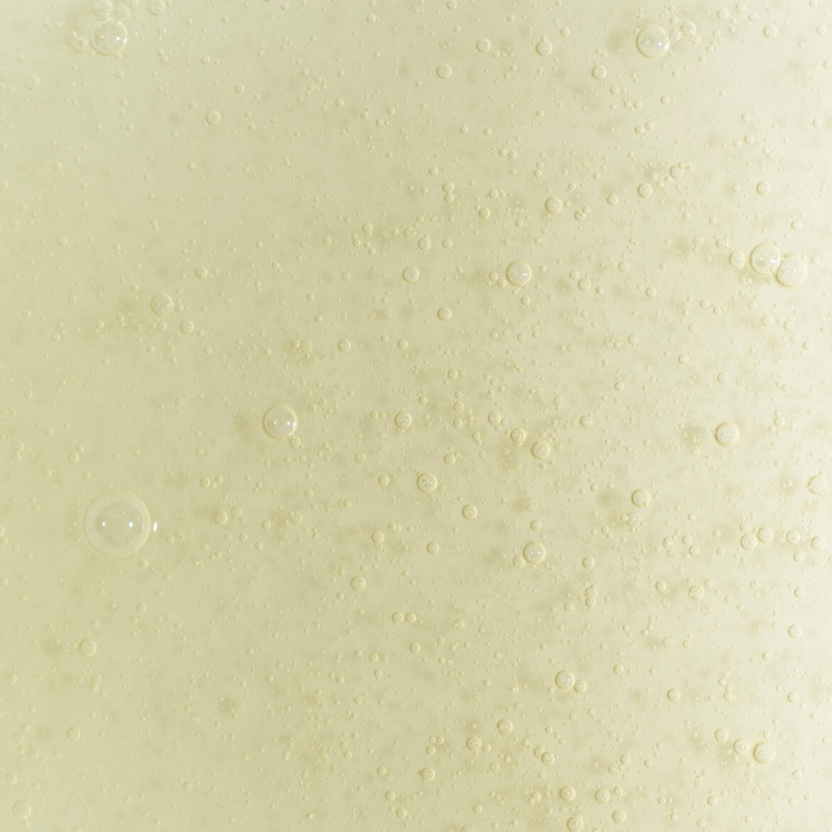 Close-up texture of UpCircle citrusy hand and body wash gel with visible bubbles and a pale yellow hue.