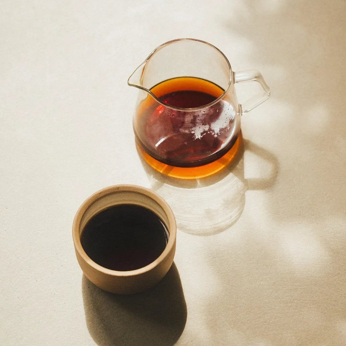 Origin Coffee Das Almas coffee served in a glass carafe and a minimalist ceramic cup on a neutral textured surface