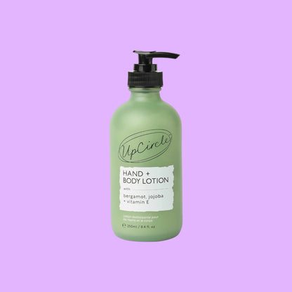 UpCircle hand and body lotion in a frosted green glass bottle with a black pump dispenser and bergamot scent label (view 2).