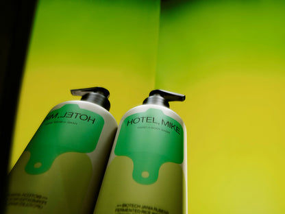 Hotel Mike sulphate-free hand and body wash in recyclable aluminium bottles with green labels against a bright yellow background