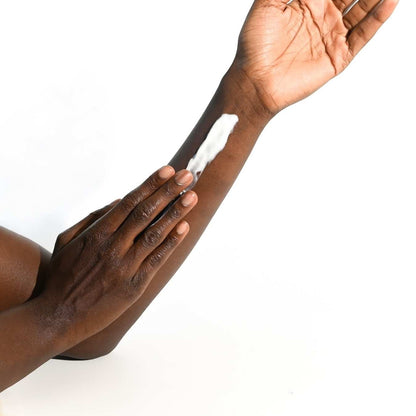 UpCircle hand and body lotion being applied to a person's arm, showing the white, fast-absorbing cream texture.