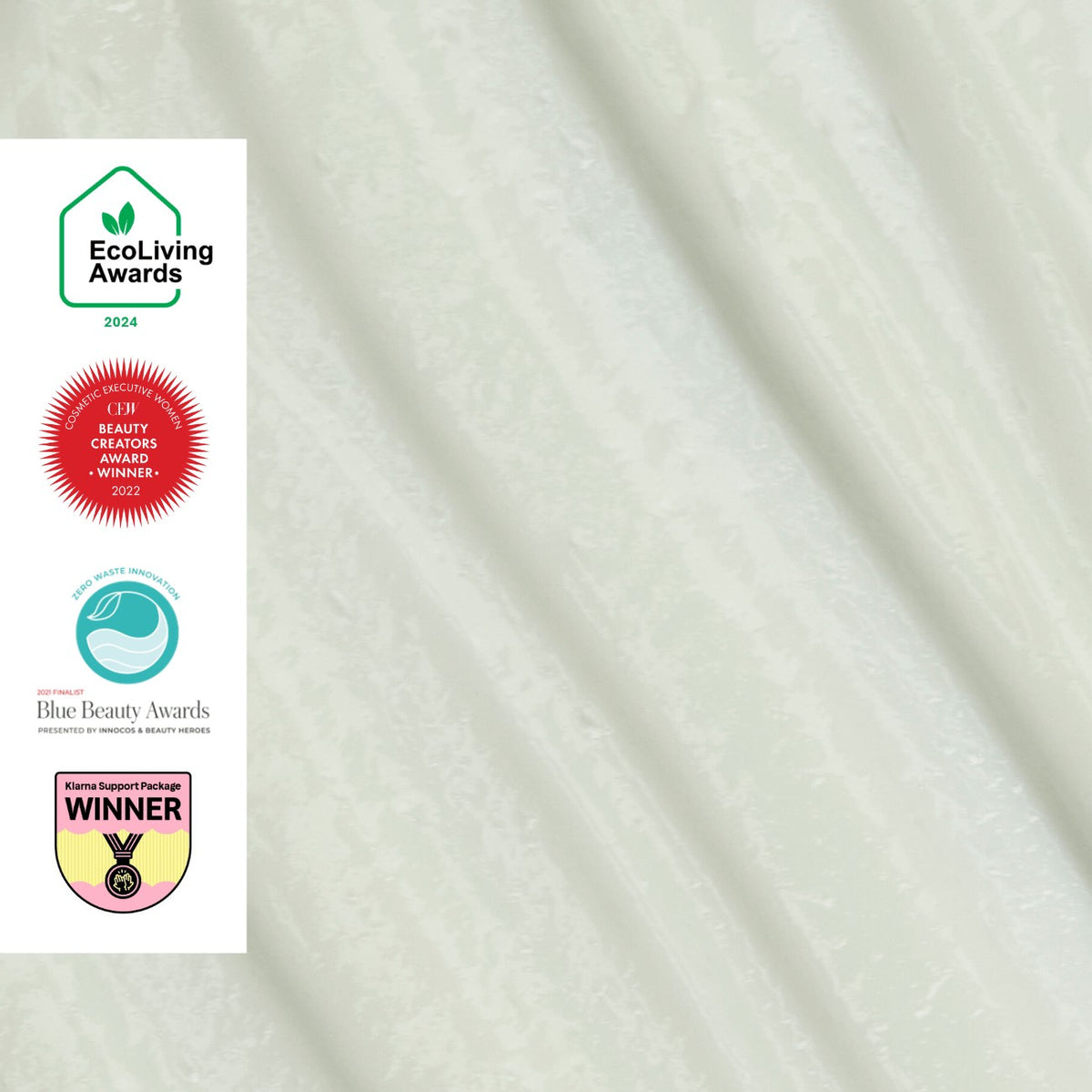 UpCircle hand and body lotion in a frosted green glass bottle featuring four eco-friendly beauty award badges.