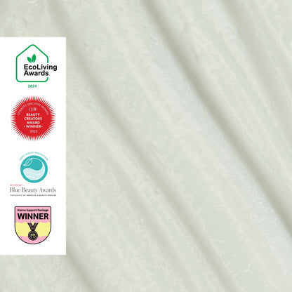 UpCircle hand and body lotion in a frosted green glass bottle featuring four eco-friendly beauty award badges.