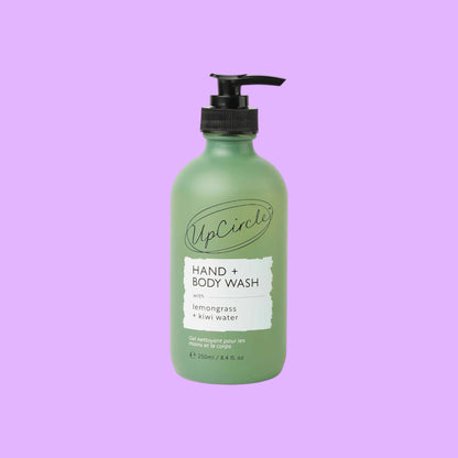 UpCircle Hand & Body Wash in a frosted green glass bottle with a black pump, featuring lemongrass and kiwi fruit water.