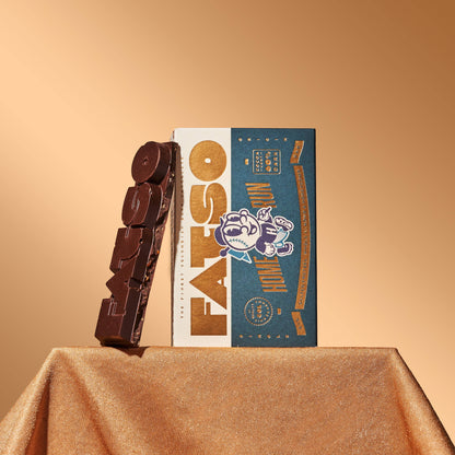 Fatso Home Run 60% dark chocolate slab with pretzel, honeycomb, and almond inclusions next to its branded packaging.
