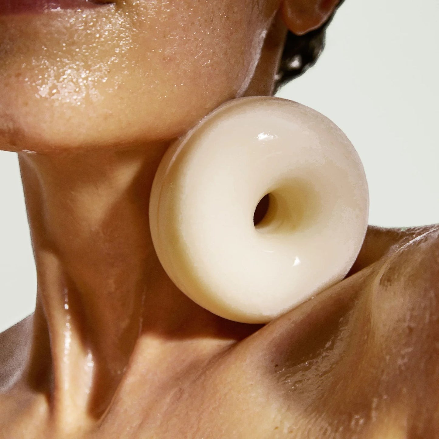 Kinfill Velvet Verveine halo-shaped body soap bar resting on a person's wet shoulder for gentle cleansing.