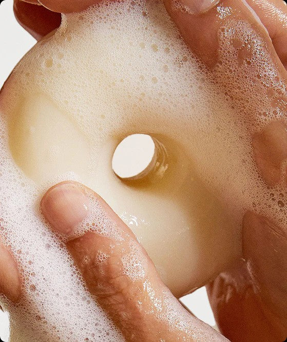 Kinfill Velvet Verveine halo-shaped body soap bar lathered with rich white foam in hands