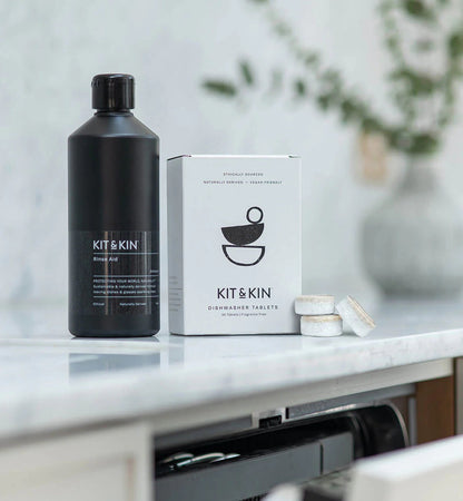 Kit & Kin eco-friendly dishwasher rinse aid bottle and tablet box on a marble kitchen counter