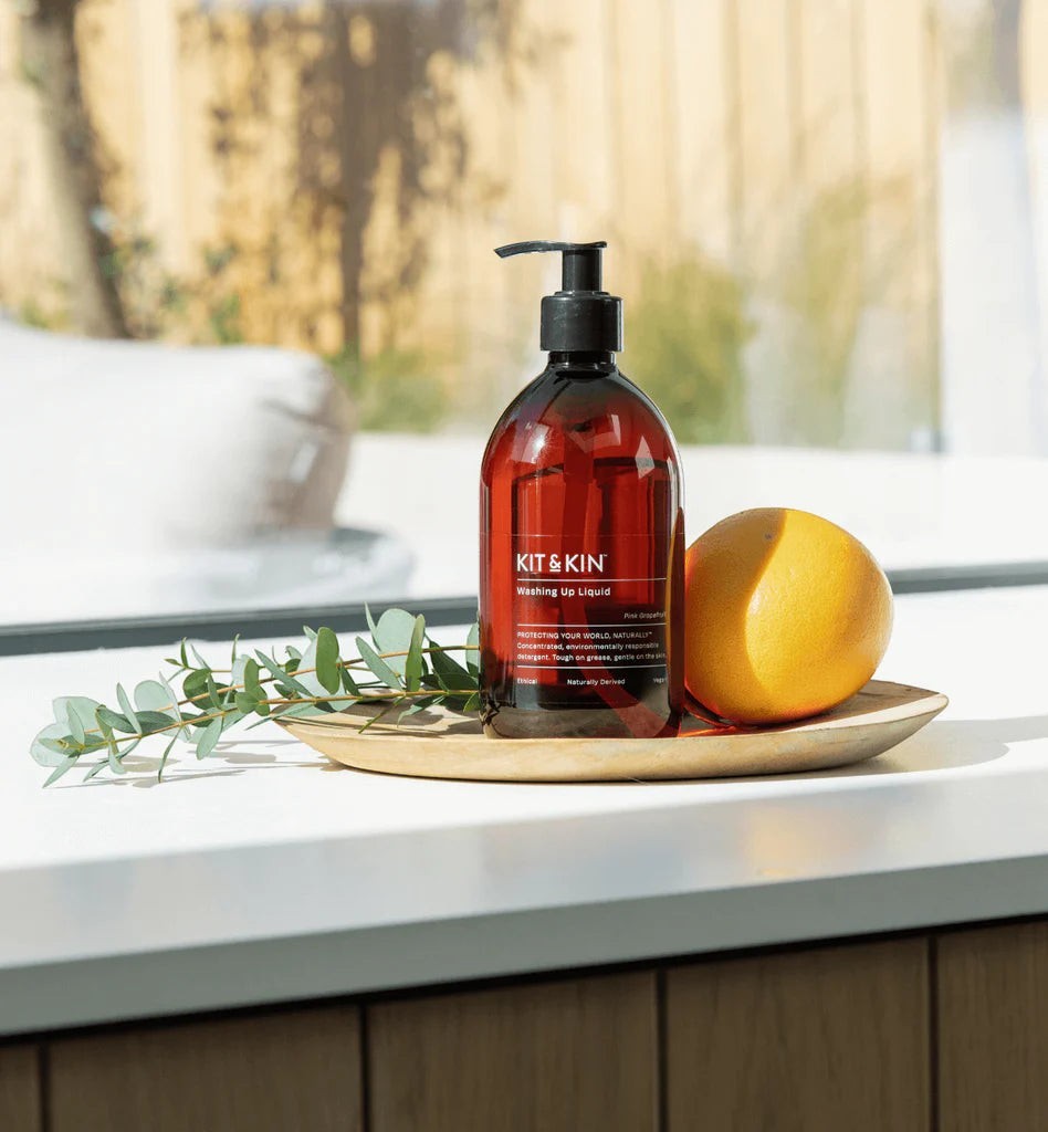 Kit & Kin plant-based washing-up liquid in an amber pump bottle with a fresh orange and eucalyptus sprig