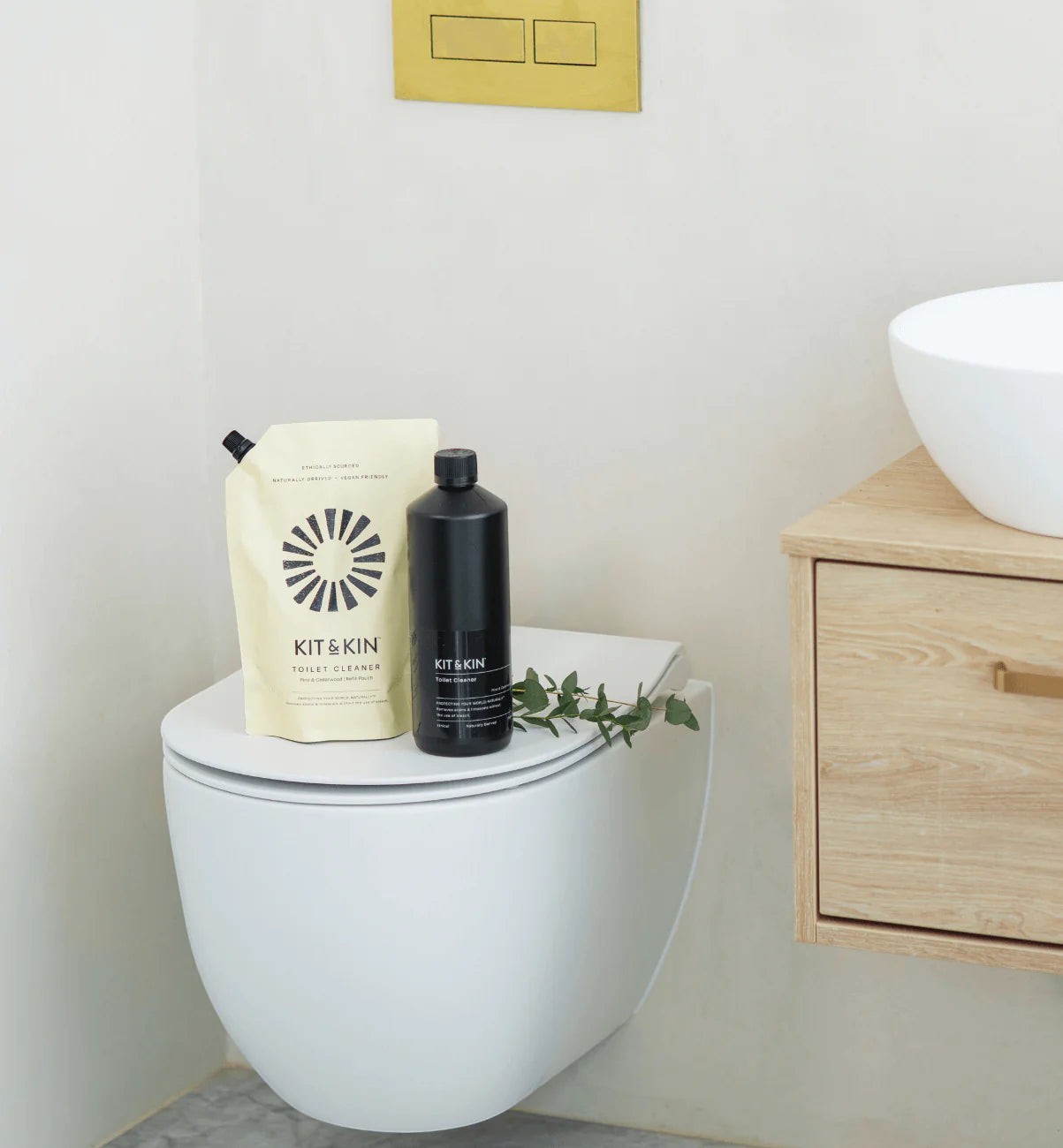 Kit & Kin plant-based toilet cleaner bottle and refill pouch with pine and cedarwood scent on a toilet seat