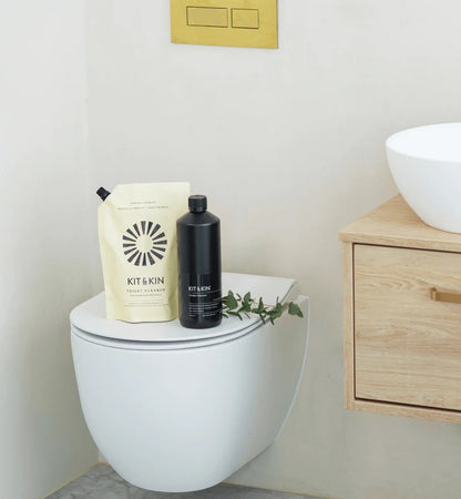 Kit & Kin plant-based toilet cleaner bottle and refill pouch with pine and cedarwood scent on a toilet seat