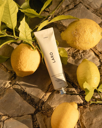 Laro London naturally whitening toothpaste in a recyclable aluminium tube surrounded by fresh lemons.