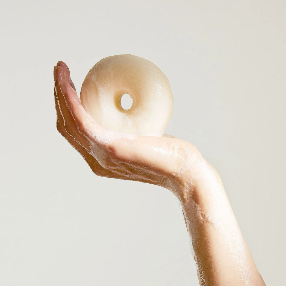 Kinfill Lavender Fields hand soap bar held in a lathered hand, featuring a donut-shaped solid plant-based soap.