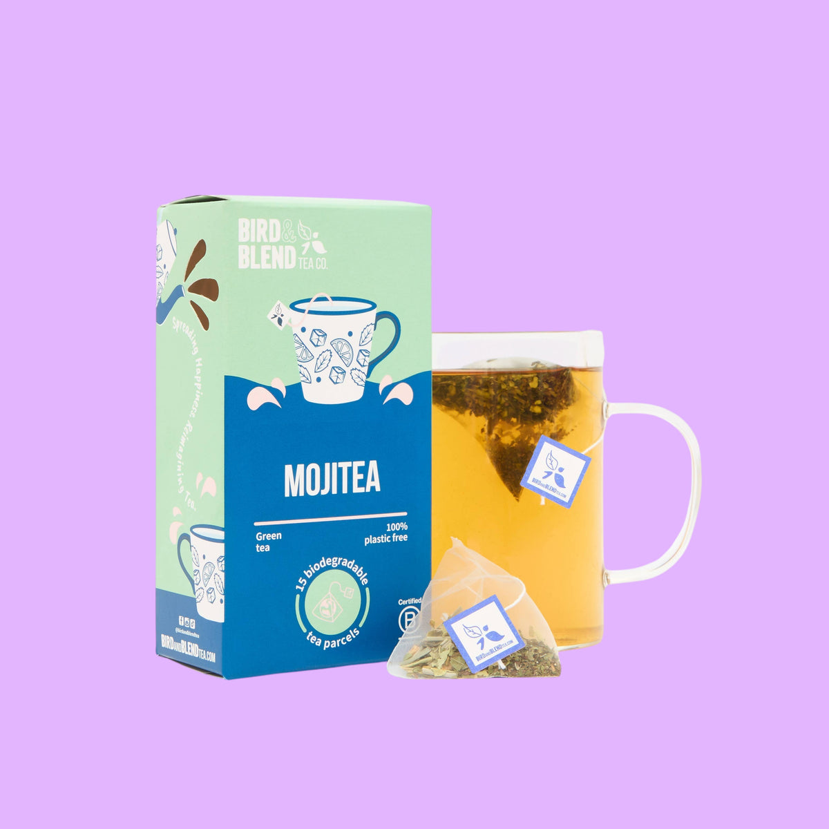 Bird & Blend Tea Co. MojiTEA green tea box with a glass mug of brewed tea and a biodegradable pyramid tea bag on a light background