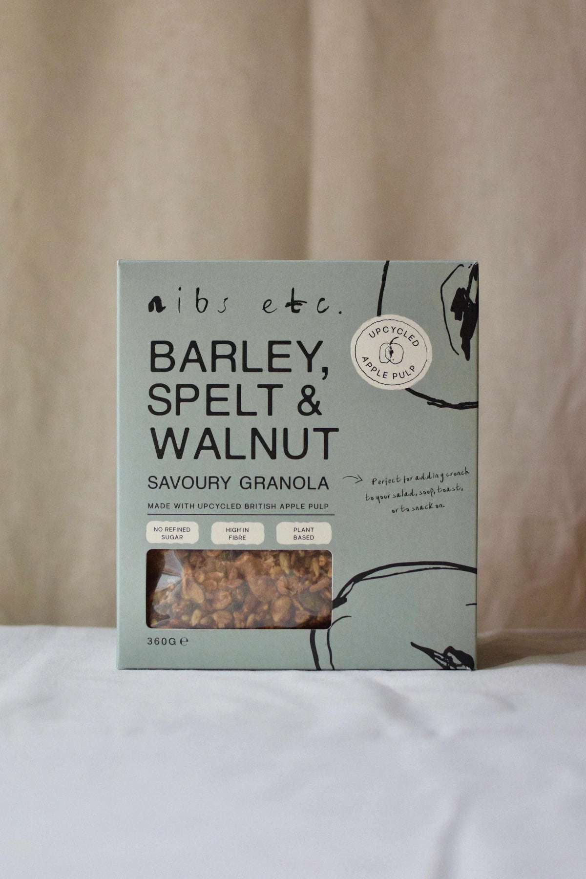 Nibs Etc. savoury granola with barley, spelt, and walnuts in a sustainable, light green cardboard box.