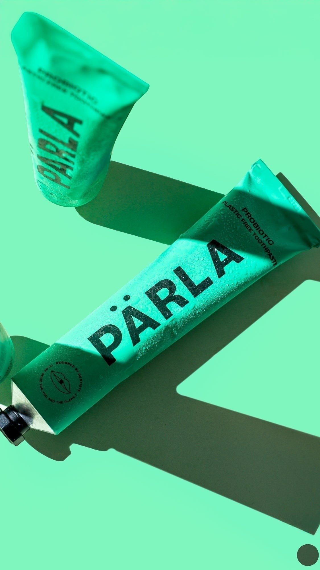 Pärla probiotic toothpaste in a green plastic-free tube with bold black branding on a matching green background.