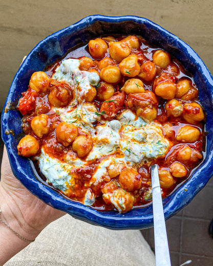 Bold Bean Co Queen Chickpeas served in a rustic blue bowl with tomato sauce, creamy yogurt, and fresh herbs