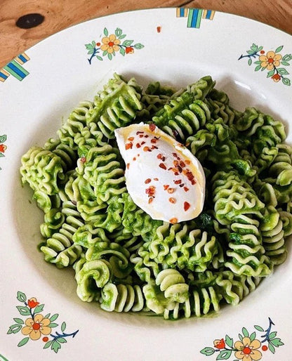 Northern Pasta Co. Radiatori pasta tossed in vibrant green pesto sauce topped with a dollop of creamy cheese and chili flakes.