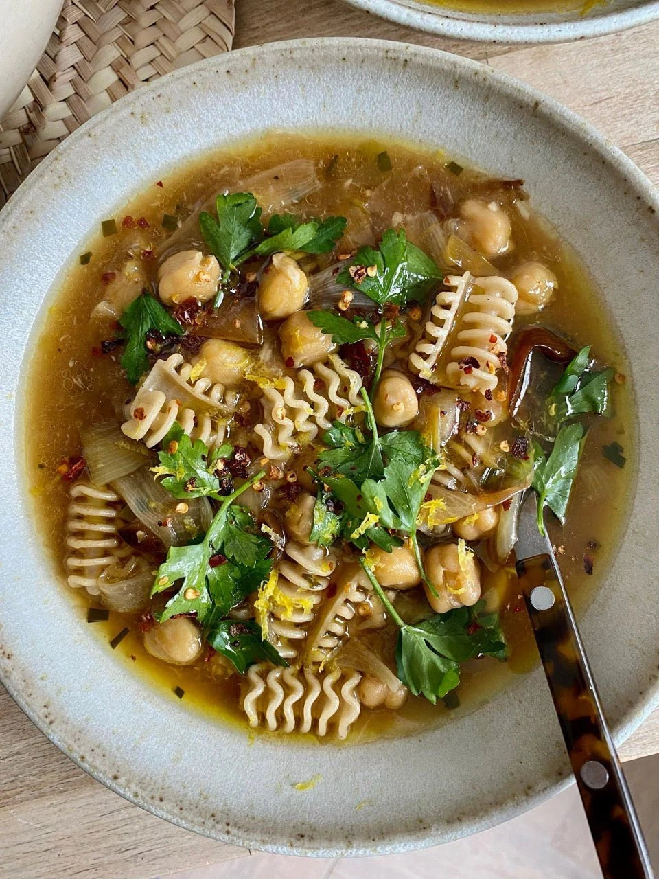 Northern Pasta Co. Radiatori pasta in a savory chickpea and herb soup served in a rustic ceramic bowl with a tortoiseshell spoon.