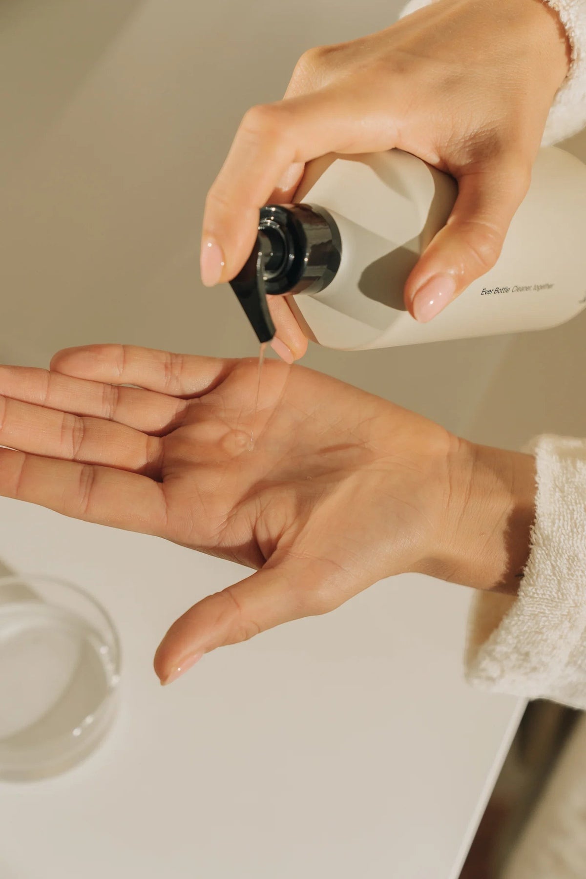 Kinfill Santal & Cedar hand wash being dispensed from a minimalist refillable bottle into a person's palm
