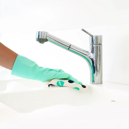 Seep cleaning kit featuring a hand in a mint green rubber glove wiping a white kitchen sink with a patterned cloth