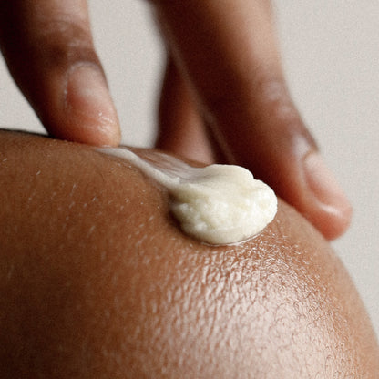 Mirror Water shea butter body balm melting into skin on an elbow, showing a rich, creamy texture for deep hydration.