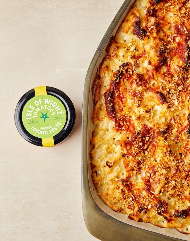 Isle of Wight Tomatoes jar of Isle of Wight Smoked Tomato Pesto next to a golden baked pasta dish with a crispy breadcrumb topping