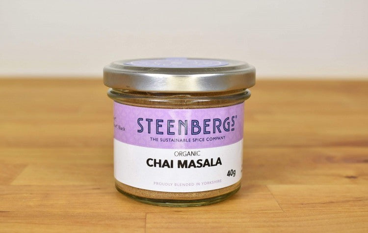 Steenbergs organic masala chai spice blend in a recyclable glass jar on a wooden surface