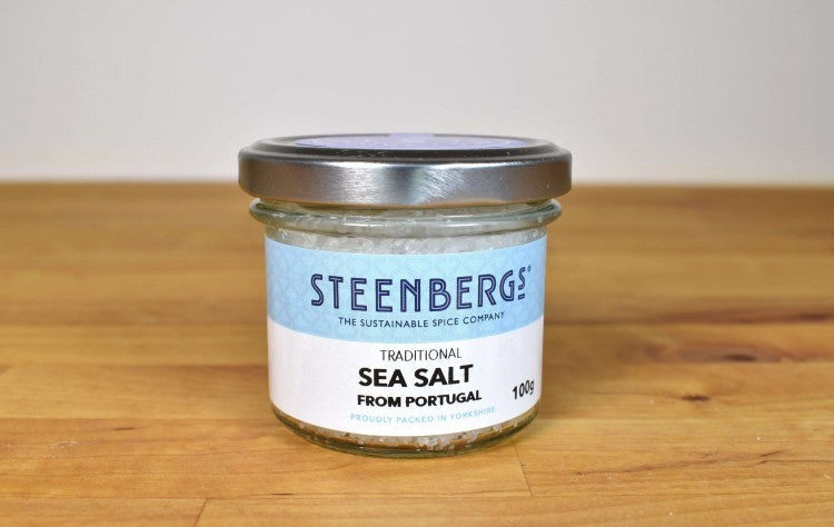 Steenbergs traditional unrefined sea salt flakes in a glass jar on a wooden surface