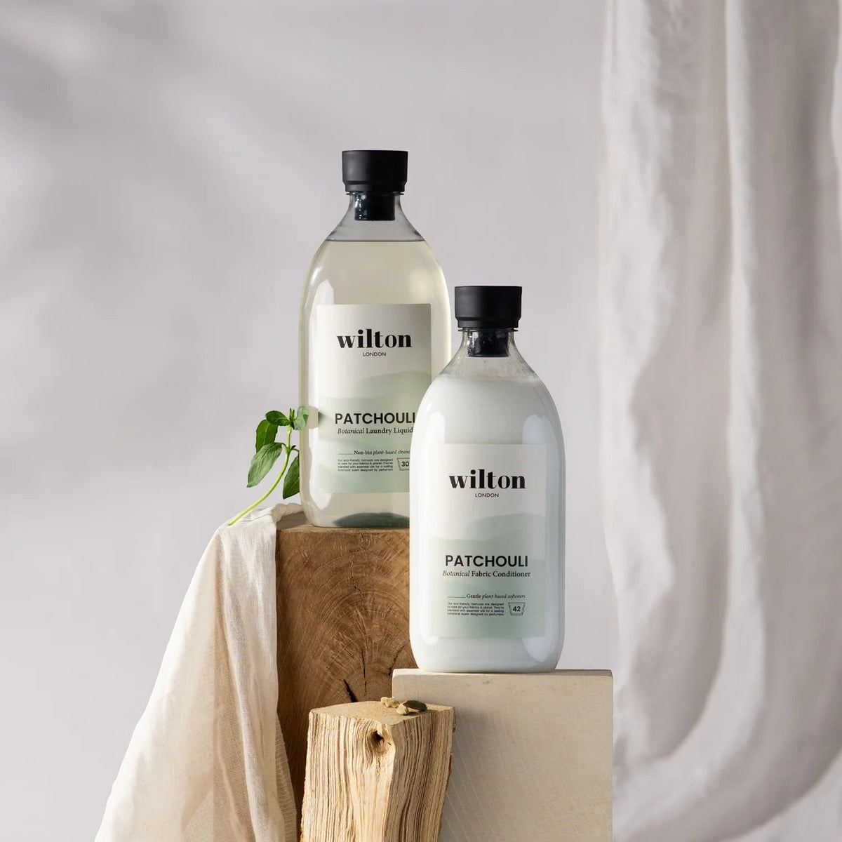 Wilton London Patchouli laundry liquid and fabric conditioner bottles on wooden blocks with linen cloth