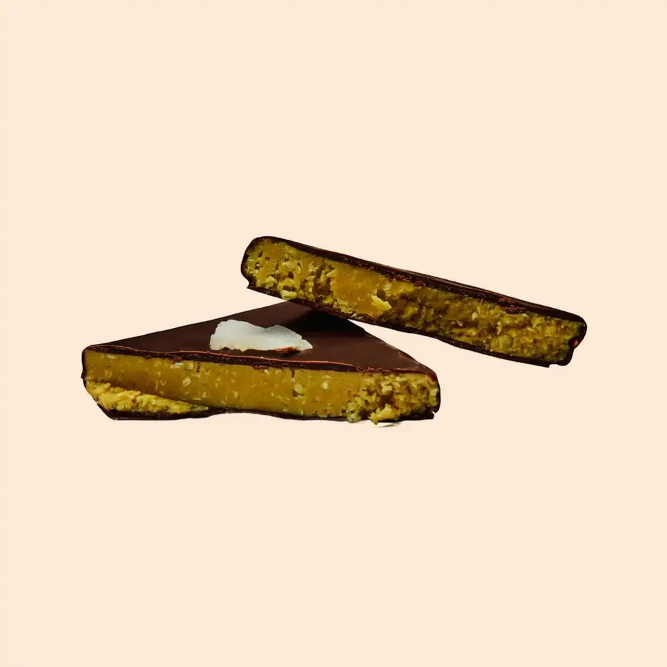 Cosmic Dealer dark chocolate bar with coconut, turmeric, and almond butter filling, shown in cross-section.