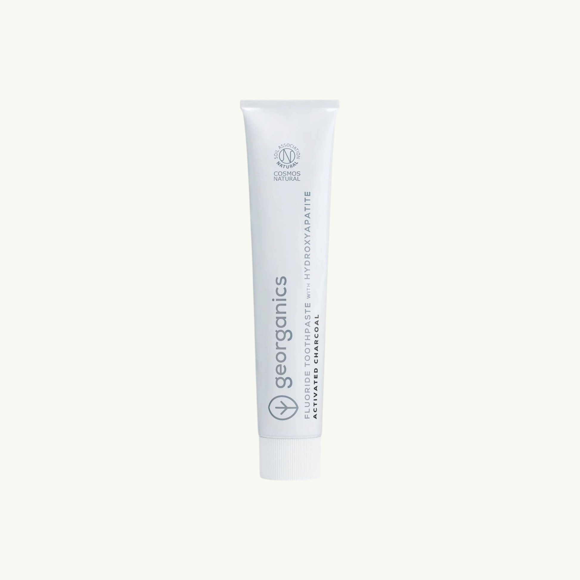 georganics activated charcoal toothpaste tube with hydroxyapatite and fluoride on off-white background