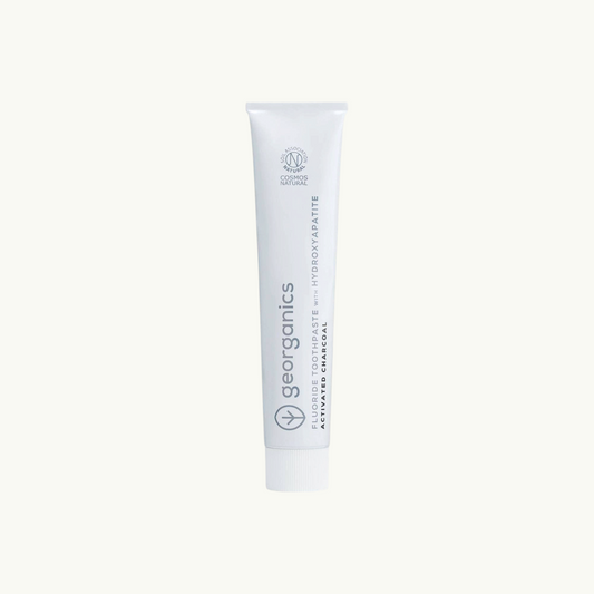 georganics activated charcoal toothpaste tube with hydroxyapatite and fluoride on off-white background