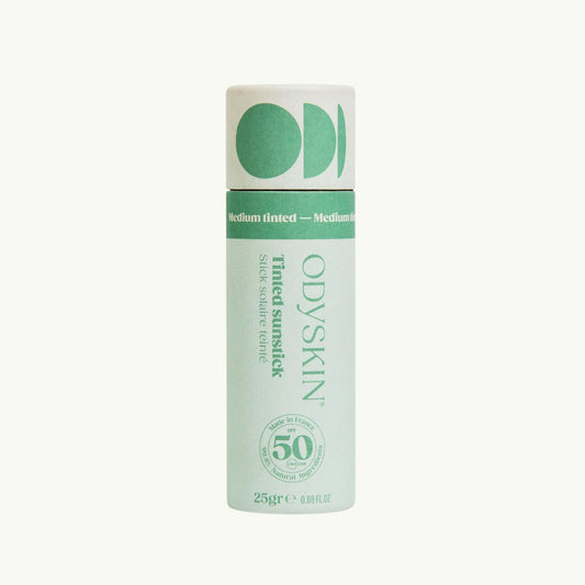 Odyksin SPF 50 tinted mineral sunscreen stick in a light green cardboard tube for easy application on sensitive areas.