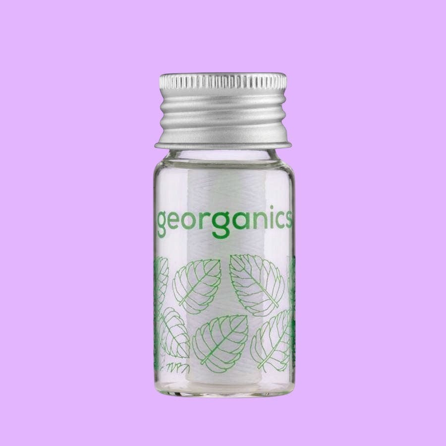 georganics dental floss in a refillable glass dispenser with an aluminium lid and spearmint leaf print design