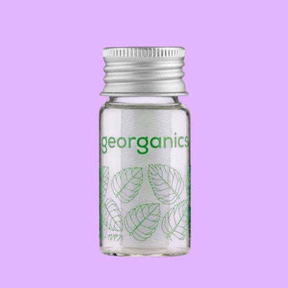 georganics dental floss in a refillable glass dispenser with an aluminium lid and spearmint leaf print design