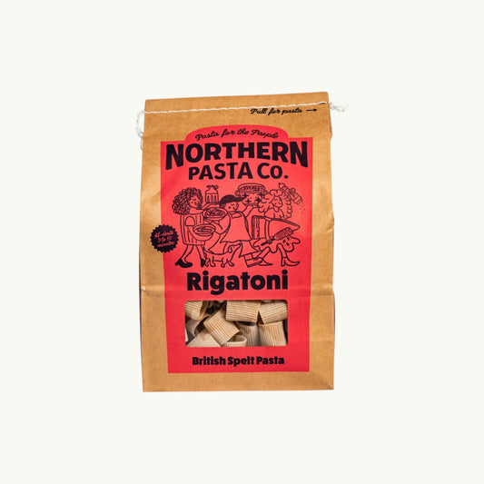 Northern Pasta Co. Rigatoni in a brown paper bag with red branding and a window showing the spelt pasta shapes.